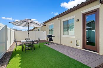 A backyard patio with a table and chairs and an umbrella